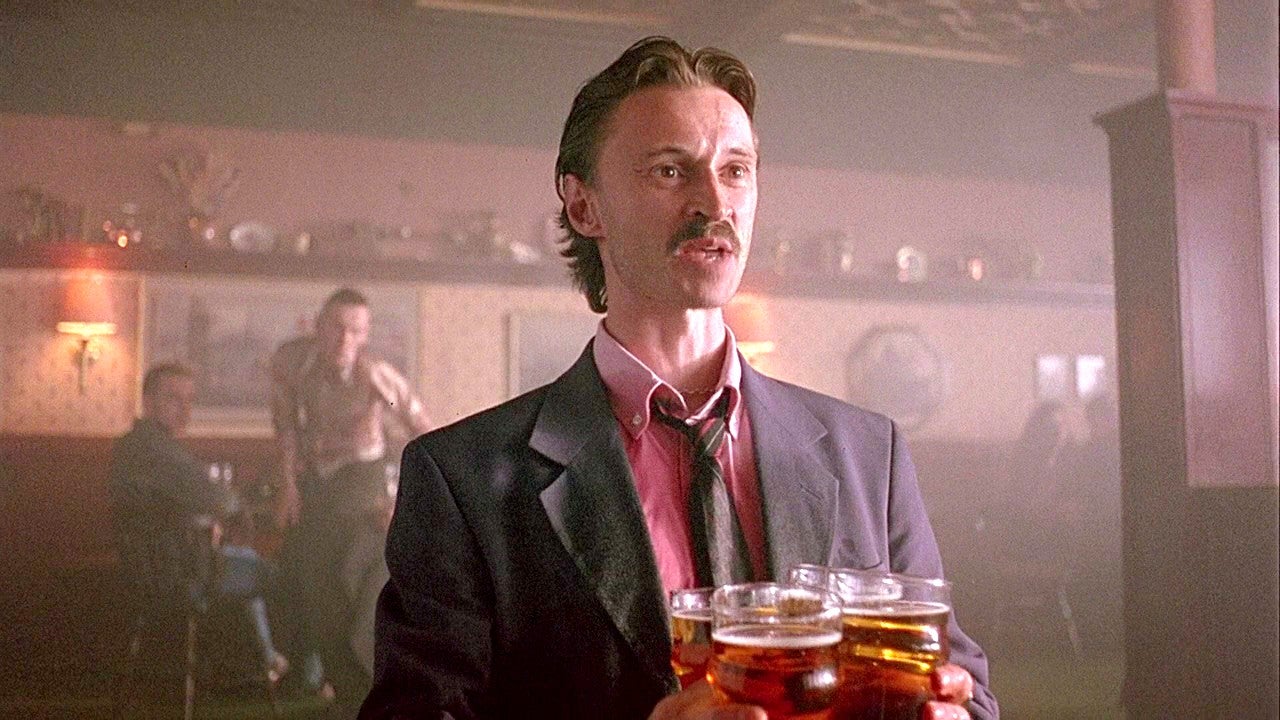 Francis Begbie, interpretado por Robert Carlyle, segura vários copos de cerveja em um pub em Trainspotting.
