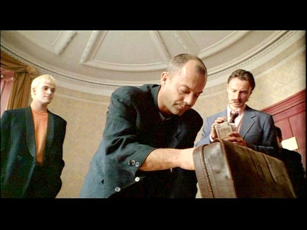 Personagens de Trainspotting observam uma mala em um quarto de hotel durante o negócio de drogas do final do filme.