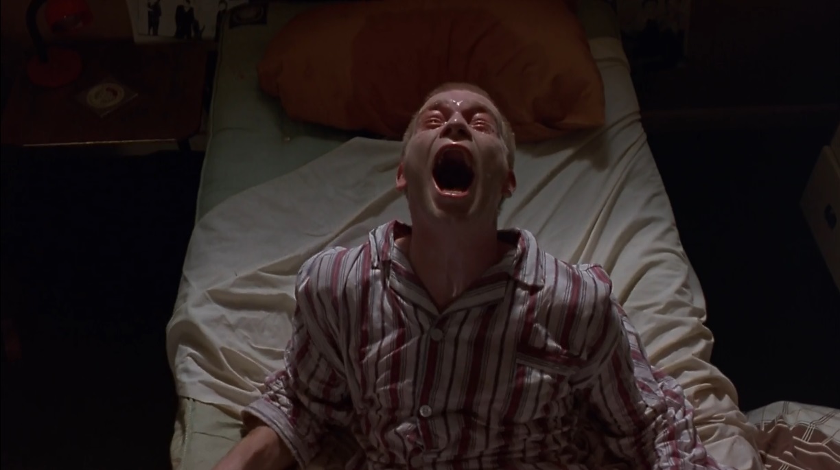 Mark Renton grita sentado na cama durante a abstinência de heroína em Trainspotting.